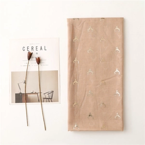 Detail of pink cotton-linen scarf featuring gold foil reindeer antler patterns on fabric