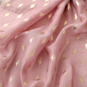 Close-up of light pink scarf fabric with shiny gold foil diamond patterns and soft texture