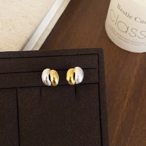 Macro detail of mixed metal earrings with brushed silver and polished gold texture