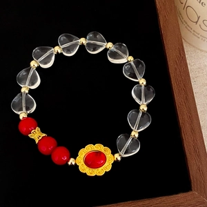 Détail d'un bracelet artisanal en cristal de cœur avec perles rouges et dorées
