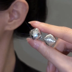 Detailed view of silver square earrings featuring textured brushed and polished mirror finishes