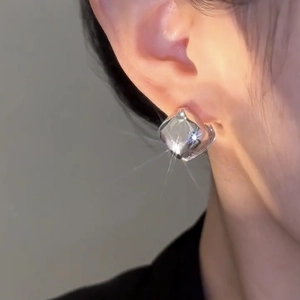 Close-up of model wearing polished silver square earrings with metallic mirror finish