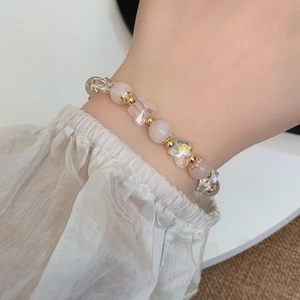 Pink crystal flower and butterfly beaded bracelet with gold accents worn on a female wrist