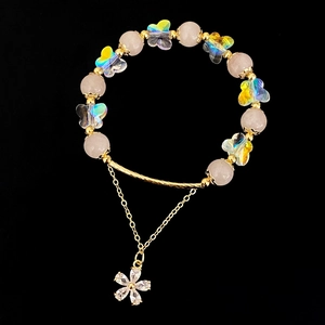 Macro shot of pink crystal beads, iridescent butterfly charms, and a diamond floral pendant