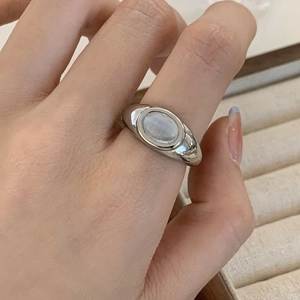 Detail of vintage silver ring with oval white cat-eye gemstone on model finger