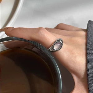 Close-up of a silver-tone ring with an oval pink cat-eye stone worn on a hand