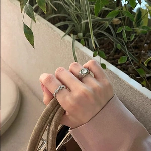 Close-up of stacked silver rings with green cat-eye stone and floral bead band