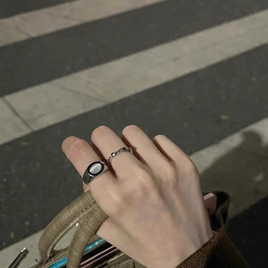 Detail view of silver ring set with oval cat eye stone and wavy band on hand
