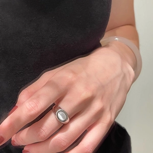 Detail of vintage cat's eye stone ring on finger paired with a translucent pink bangle