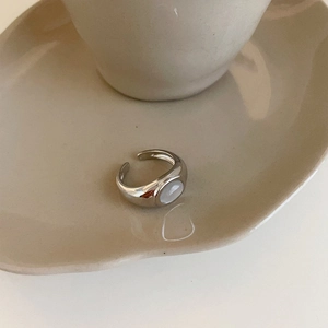 Minimalist silver open ring with oval cat's eye stone on elegant beige ceramic tray