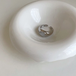 Macro shot of silver adjustable cat-eye stone ring on a minimalist ceramic tray