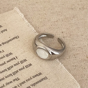 Detailed close-up of a vintage silver open ring featuring an oval opal-like white stone