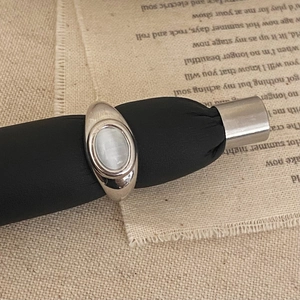 Close-up of retro silver ring with oval cat's eye stone on black leather display