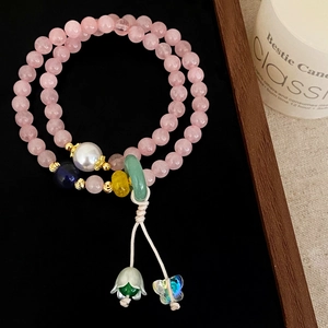 Detail of pink crystal double-strand bracelet with pearl, butterfly and floral charms