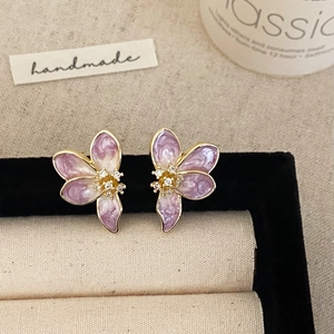 Detail of floral earrings with lavender enamel petals and white zircon centers on velvet