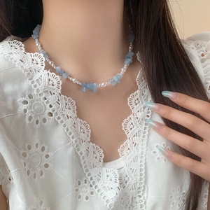 Collier élégant avec pierres bleu clair et perles blanches sur mannequin en dentelle