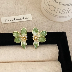 Macro shot of French style floral earrings with green enamel petals and zircon details