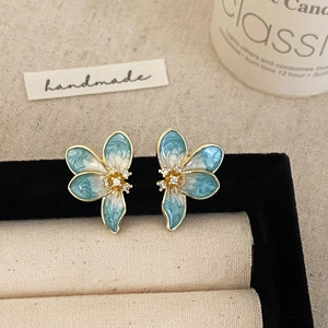 Macro detail of blue and white enamel flower stud earrings with sparkling zircon centers
