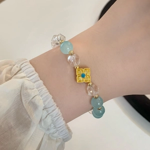 Élégant bracelet en perles bleu clair avec fleur dorée porté sur un poignet