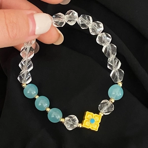 Gros plan détaillé des perles de verre bleu clair et du pendentif fleur dorée du bracelet