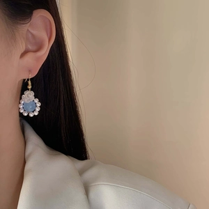 Elegant pearl and blue stone flower drop earrings on model for a chic feminine style