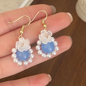 Macro shot of light blue natural stone earrings with white pearls and petal fringe details