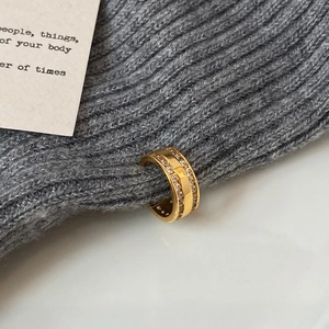 Detail der goldfarbenen Earcuff mit doppelreihigen Zirkonia auf grauem Strickgewebe