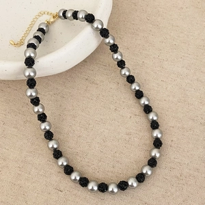 Détail du collier de perles grises et pierres volcaniques noires avec fermoir doré
