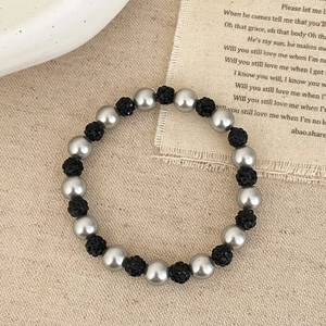 Gros plan d'un bracelet extensible avec perles argentées et boules de cristal noir