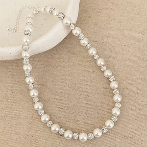 Détail du collier de perles avec boules en strass sur une assiette en céramique