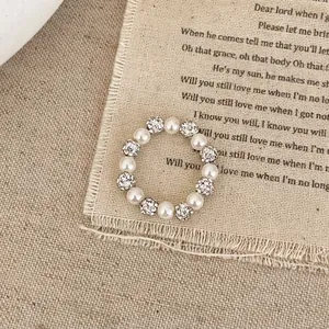 Vue détaillée d'une bague élastique en perles et strass sur un tissu en lin vintage