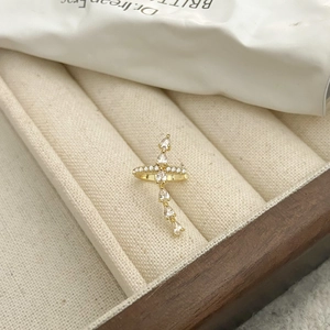 Detalle de cerca del pendiente de clip dorado con cruz de circonitas y gotas colgantes