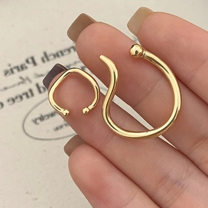 Detail of two gold-plated geometric ear cuffs showing mirror finish and minimalist design