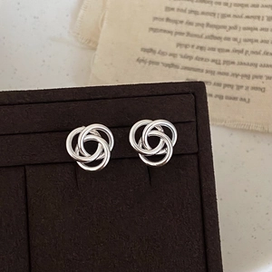 Vue macro de boucles d'oreilles argentées à trois anneaux sur un plateau de velours