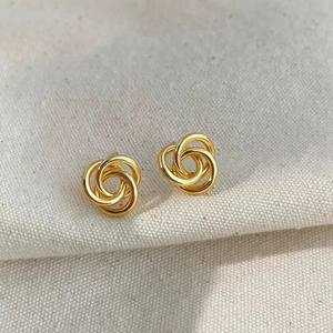 Detail of gold plated interlocking triple hoop stud earrings on linen background