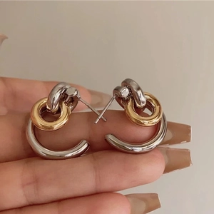 Détail de boucles d'oreilles anneaux bicolores or et argent au design géométrique