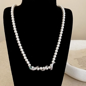 Luxury pearl necklace featuring a diamond-encrusted snake pendant with green gem eyes