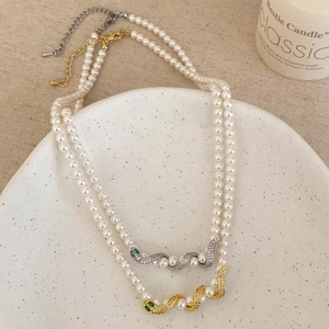 Luxury pearl necklace featuring a sparkling diamond-set snake pendant with green eyes