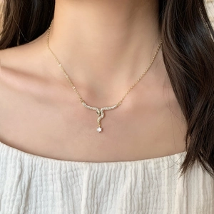Elegant gold snake pendant necklace with pavé zircons worn on model collarbone