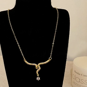 Close-up of golden snake pendant necklace with pavé crystals and sparkling round drop stone
