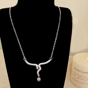 Detail of silver snake pendant necklace with pavé crystals on black velvet display
