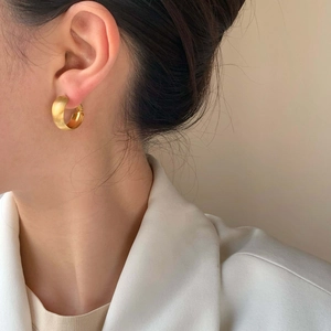 Elegant gold matte brushed hoop earrings for women worn with a stylish white suit