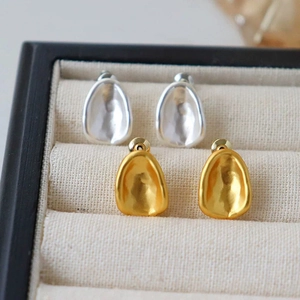Macro shot of gold and silver irregular concave oval stud earrings with matte finish