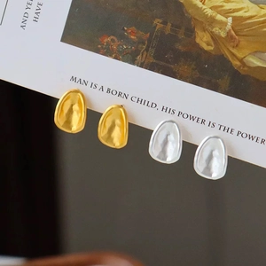 Matte irregular oval stud earrings in gold and silver with a unique hammered metal texture
