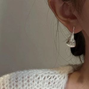 Detail shot of silver flame-shaped earrings with vertical textured finish on a model