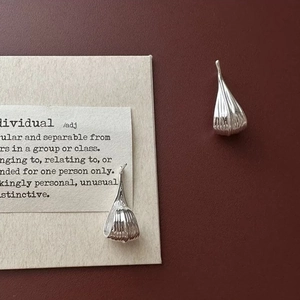 Detailed close-up of silver water drop earrings featuring elegant pleated textures