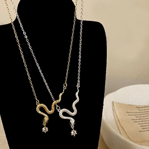 Elegant gold and silver snake necklaces with zircon pendant on black jewelry bust
