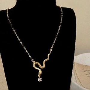 Detailed close-up of a gold snake pendant necklace with zircon inlay on a black bust