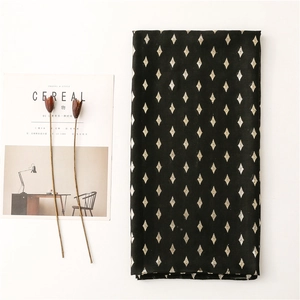 Detail of elegant black scarf with gold geometric diamond pattern and smooth texture