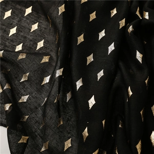 Close-up of lightweight black fabric scarf with shiny gold foil diamond patterns